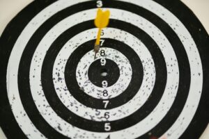 Close-up of a dart hitting the bullseye on a black and white target board symbolizing success.